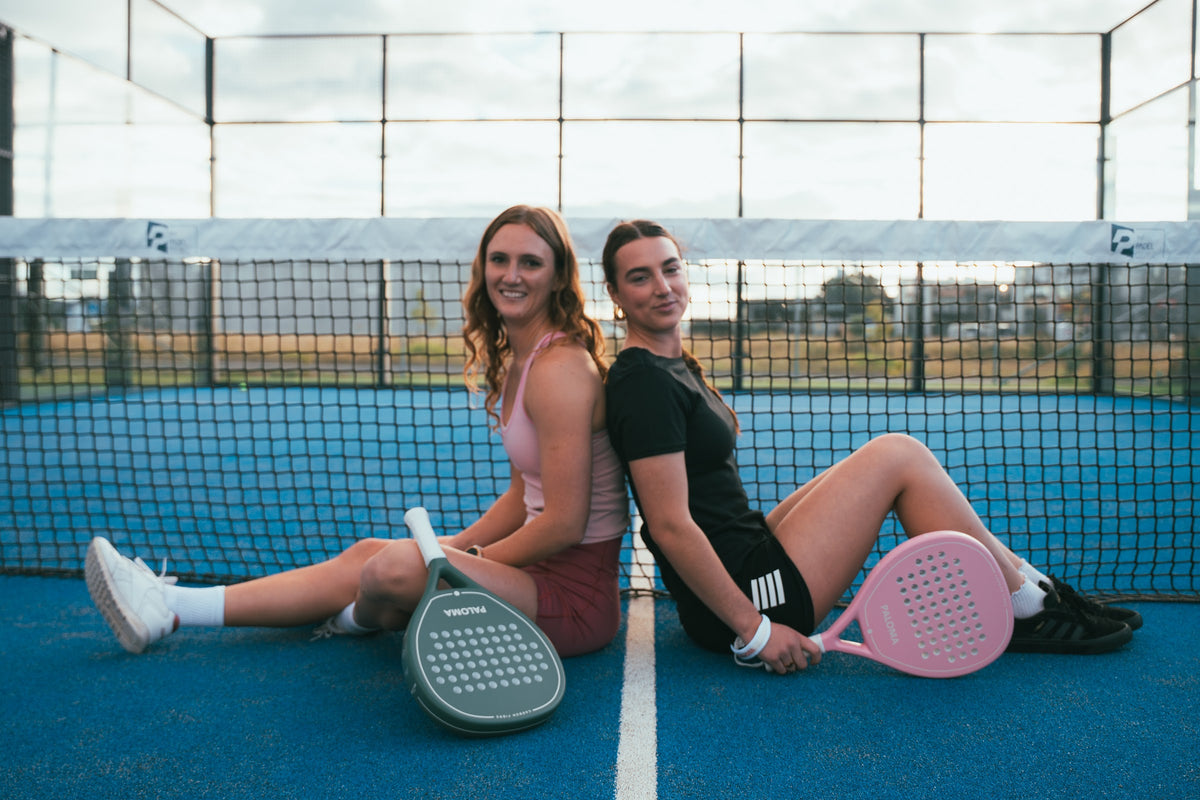 Two friends with Paloma rackets on the padel court