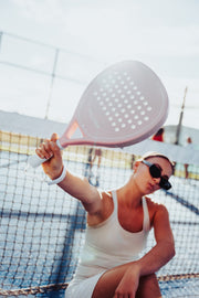 Paloma Pink racket held towards the camera on a padel court