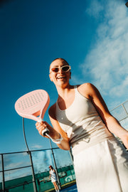 Smiling player holding a Paloma Pink padel racket on court